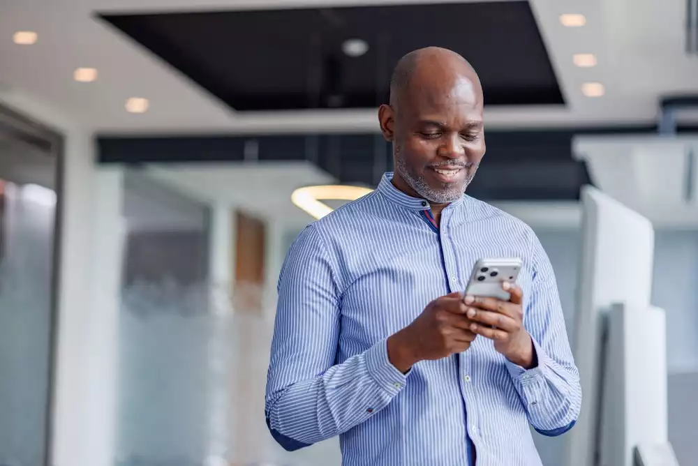 A businessman smiles down at his phone.