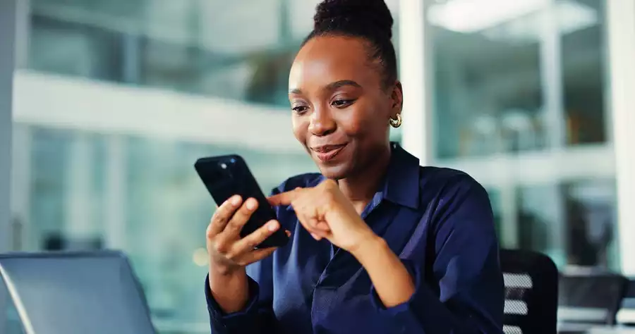 A smiling woman takes a phone call in an office setting